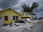 A car sits half-buried in the sand at Bradenton Beach, which was being cleaned up before evacuation orders were issued for Hurricane Milton. 