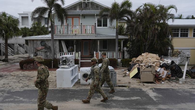 Members of the Florida Army National Guard check for any remaining residents in nearly-deserted Bradenton Beach, where piles of debris from Hurricane Helene flooding still sits outside damaged homes ahead of the arrival of Hurricane Milton, Tuesday, Oct. 8, 2024, on Anna Maria Island, Fla. (AP Photo/Rebecca Blackwell)