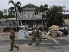 Members of the Florida Army National Guard check for any remaining residents in nearly-deserted Bradenton Beach, where piles of debris from Hurricane Helene flooding still sits outside damaged homes ahead of the arrival of Hurricane Milton, Tuesday, Oct. 8, 2024, on Anna Maria Island, Fla. (AP Photo/Rebecca Blackwell)