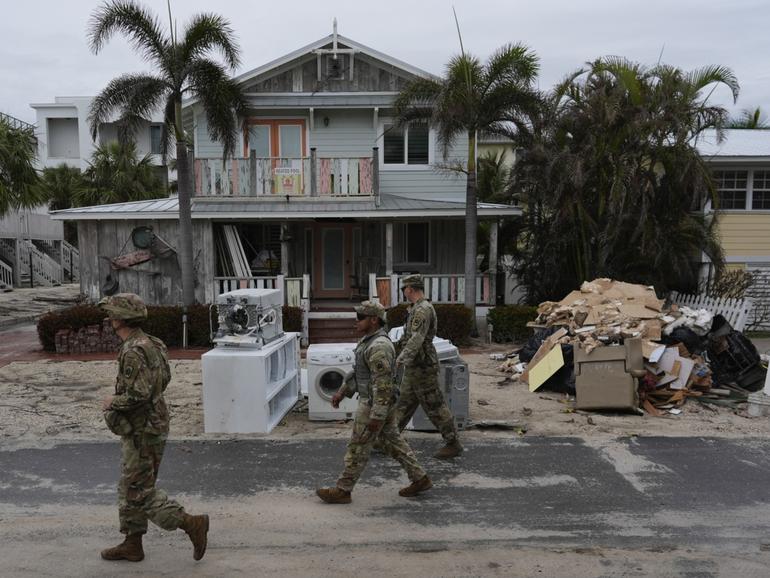 Members of the Florida Army National Guard check for any remaining residents in nearly-deserted Bradenton Beach, where piles of debris from Hurricane Helene flooding still sits outside damaged homes ahead of the arrival of Hurricane Milton, Tuesday, Oct. 8, 2024, on Anna Maria Island, Fla. (AP Photo/Rebecca Blackwell)