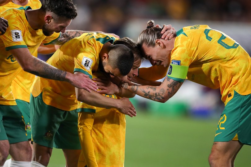 Craig Goodwin celebrates a goal with teammates Aziz Behich and Jackson Irvine.