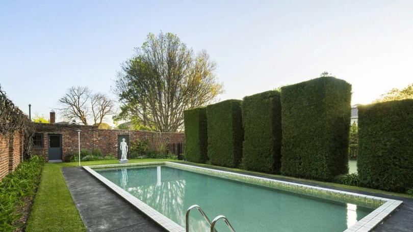 A picturesque pool and a poolhouse complement the tennis court in the backyard.