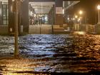 People look out at surge waters flooding the street from their building after Hurricane Milton came ashore in the Sarasota area in Fort Myers, Florida.