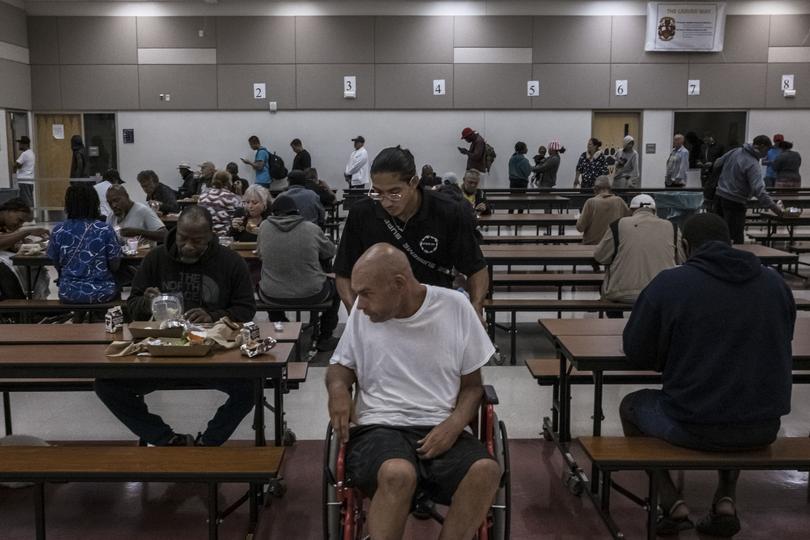 People receive help in a cafeteria of a school turned into a shelter during the hit of Hurricane Milton in Orlando.