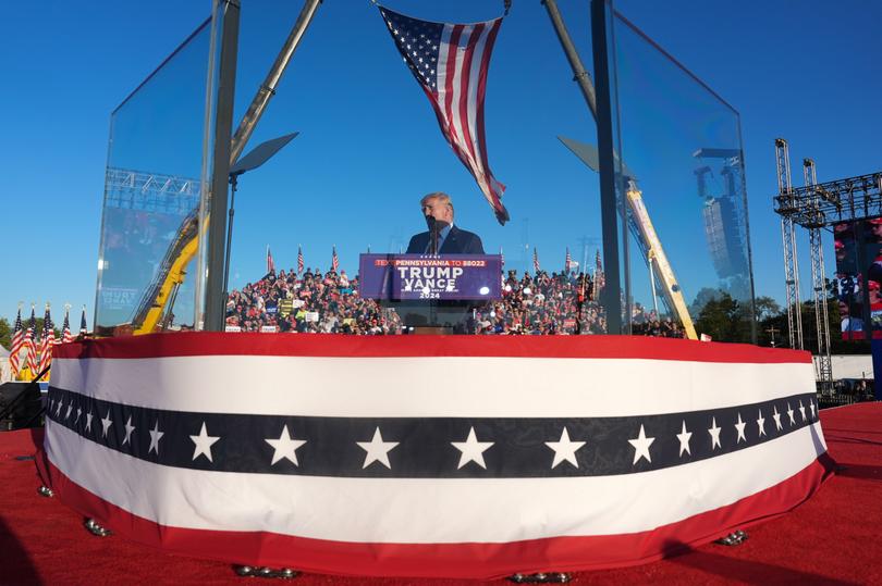 Trump speaks from behind bullet-resistant glass during a campaign event.