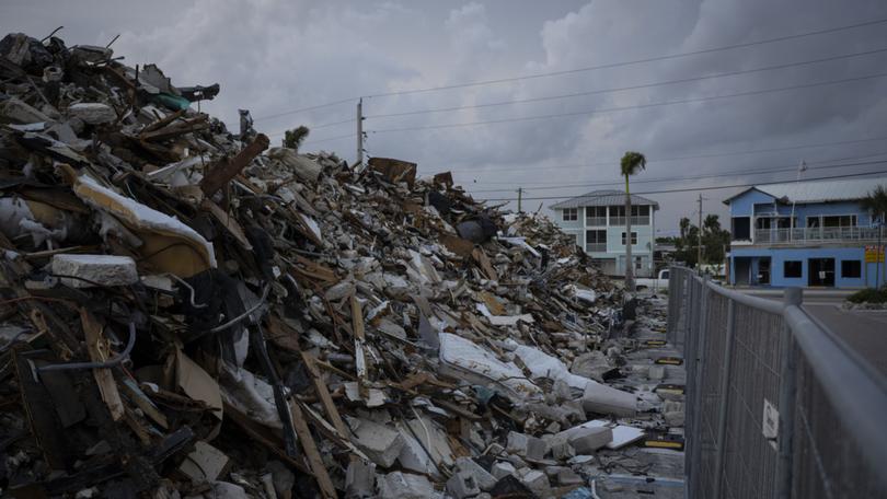 A pile of debris remains just steps from the beach in Fort Myers Beach, Fla., in June 2023, almost nine months after Hurricane Ian ravaged the area. MUST CREDIT: Thomas Simonetti for The Washington Post