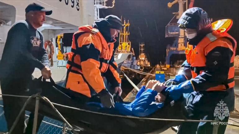 Emergency workers pull Mikhail Pichugin ashore after he was rescued by a fishing vessel. 