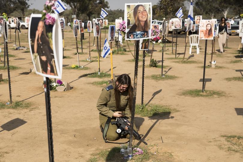 A soldier mourns near a photo of a deceased relative at the Nova music festival site.