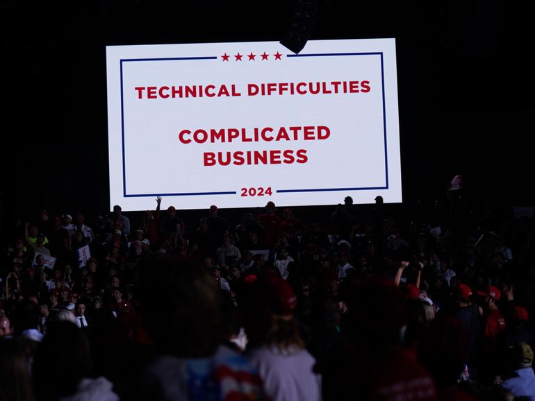 A screen makes note of technical difficulties when microphones stopped working during a Trump campaign event in Detroit.