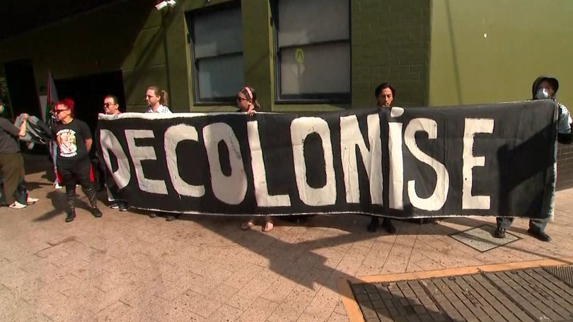 Protesters held up a banner reading “decolonise”.
