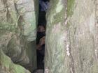 A woman has become trapped upside down between two boulders after attempting to retrieve her phone. 