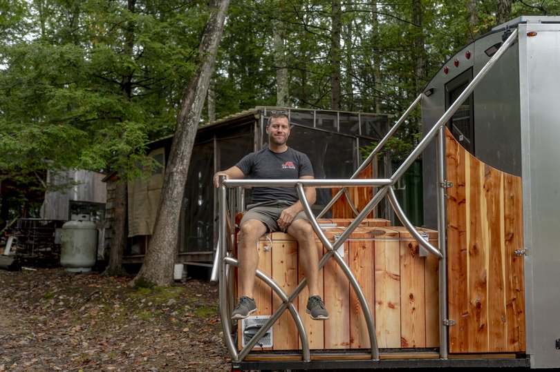 Brandon Barrett sits on a mobile sauna (with a built-in cold plunge!) that he built. 