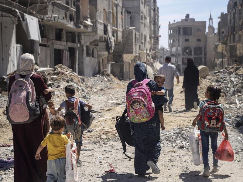 Palestinian women and children walk through destruction in Gaza