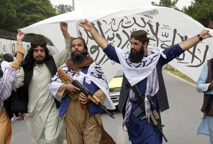 Taliban fighters hold their flag as they celebrate one year since they seized the Afghan capital, Kabul, in front of the U.S. Embassy in Kabul, Afghanistan, Monday, Aug. 15, 2022. 