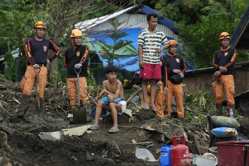 Rescuers and villagers watch retrieval operations on Saturday, Oct. 26, 2024 after it was struck by a landslide triggered by Tropical Storm Trami in Talisay, Batangas province, Philippines. 