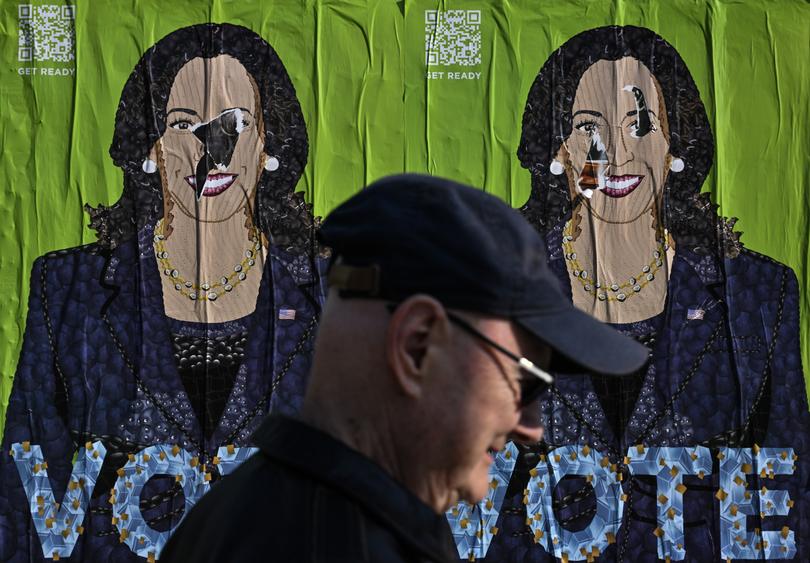 A pedestrian passes a Kamala Harris poster along a sidewalk in Philadelphia on Oct. 12. 