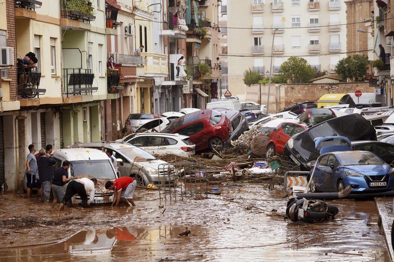 Residents look at cars piled up after being swept away by floods.