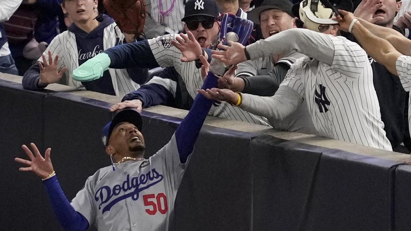 Fans interfere with a foul ball caught by Los Angeles Dodgers right fielder Mookie Betts. (AP PHOTO)