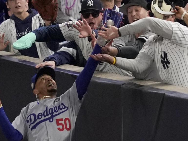 Fans interfere with a foul ball caught by Los Angeles Dodgers right fielder Mookie Betts. (AP PHOTO)