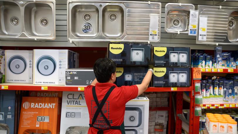 A bunnings worker stacks shelves at the hardware store