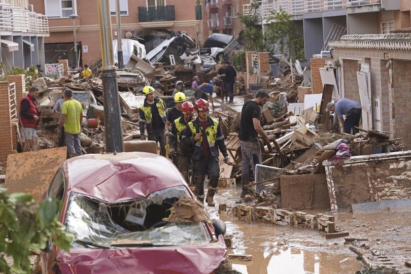 Firefighters walk as locals try to clear up the damage after floods in Massanassa, just outside of Valencia.