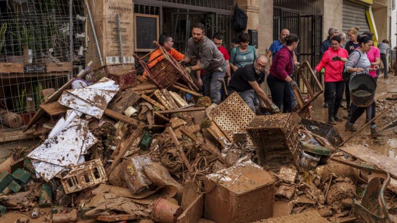 People clean mud from a flooded shop