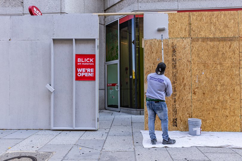 A man paints plywood outside of Blick Art Materials on 13th and I streets. 