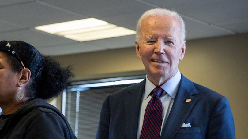 US President Joe Biden winks as he waits in line to vote inside a polling station in New Castle, Delaware.