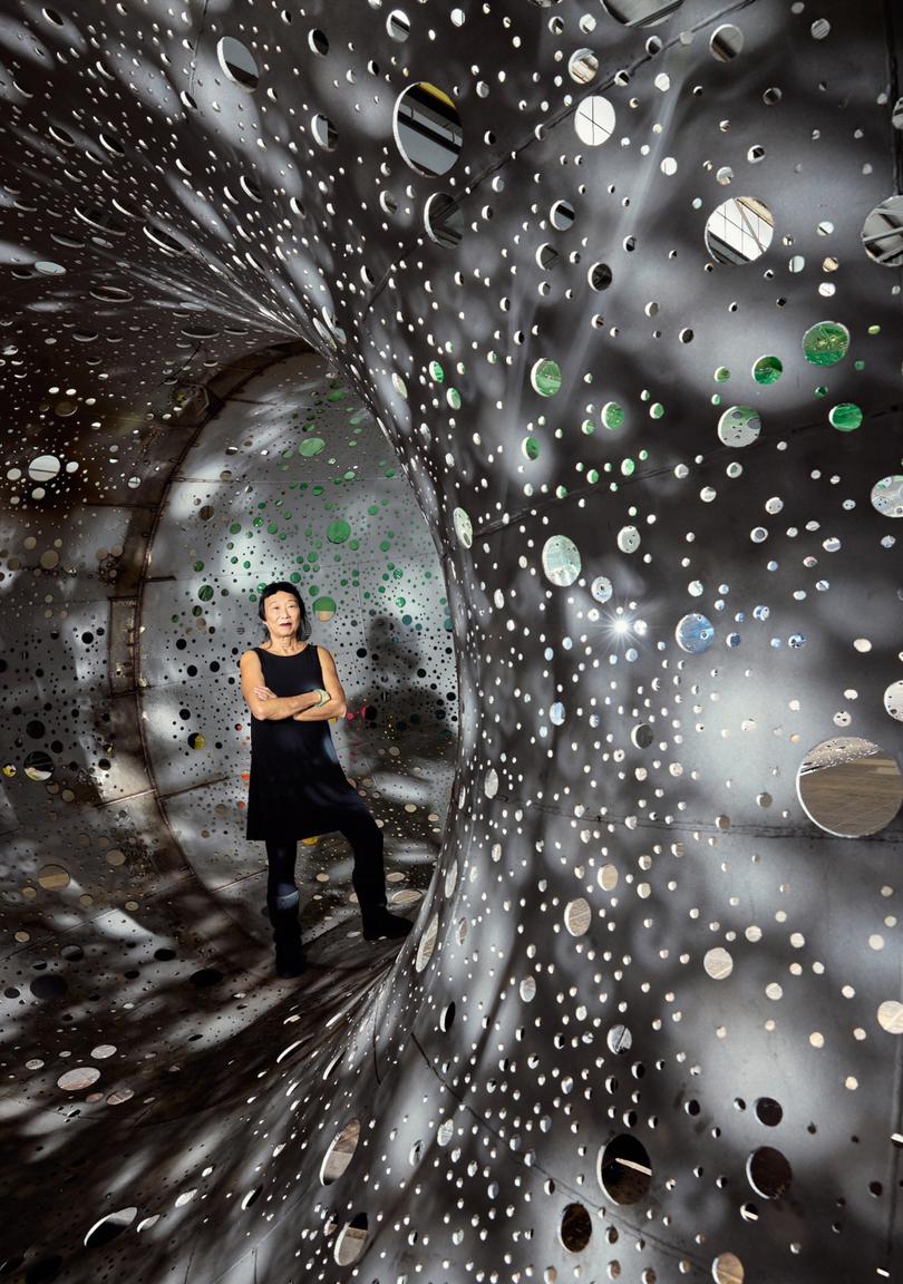 Lindy Lee stands within her sculpture at the National Gallery of Australia, Canberra.