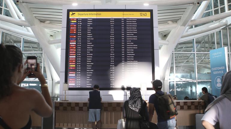 Passengers look at a flight information board at Ngurah Rai International Airport in Bali, Indonesia.