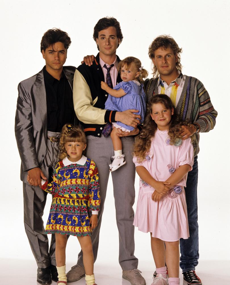 Full House stars John Stamos, Mary-Kate/ Ashley Olson, Bob Saget, Dave Coulier, Jodie Sweetin, and Candace Cameron Bure as they were during the show’s first run between 1987 and 1995.