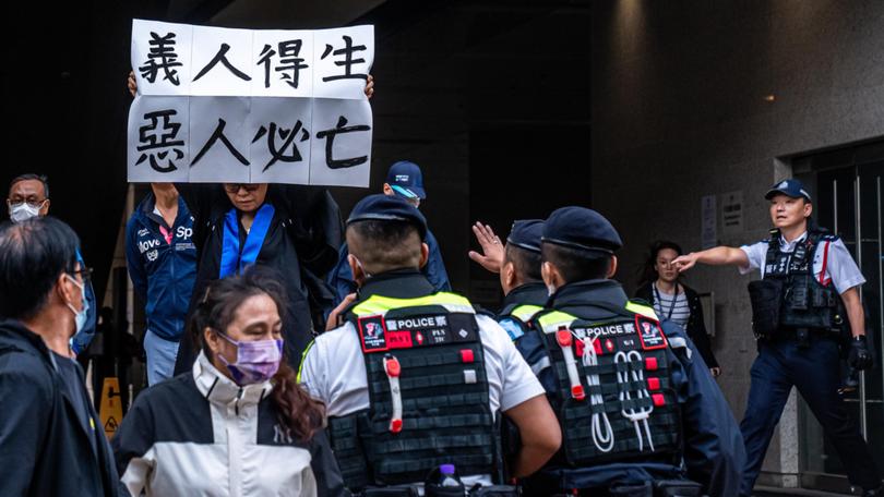 Elsa Wu, the foster mother of one of the defendants Hendrick Lui, holds a banner in protest while leaving the West Kowloon Court following a sentencing hearing for 45 pro-democracy activists in Hong Kong, China, on Tuesday, Nov. 19, 2024. 