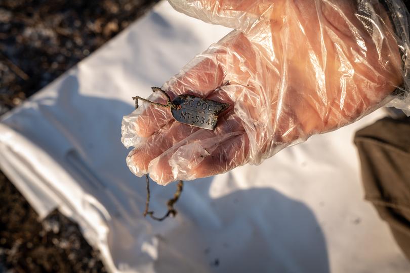 A member of a humanitarian team that collects the bodies of soldiers shows a Russian’s military I.D. tag near Koroviy Yar, Ukraine, Jan. 7, 2023. 