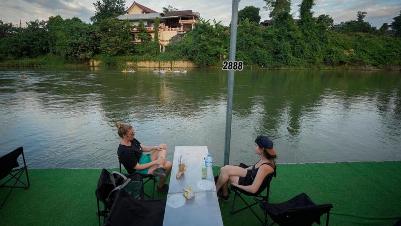 Foreign tourists drink beer at a bar near a river in Vang Vieng, Laos.