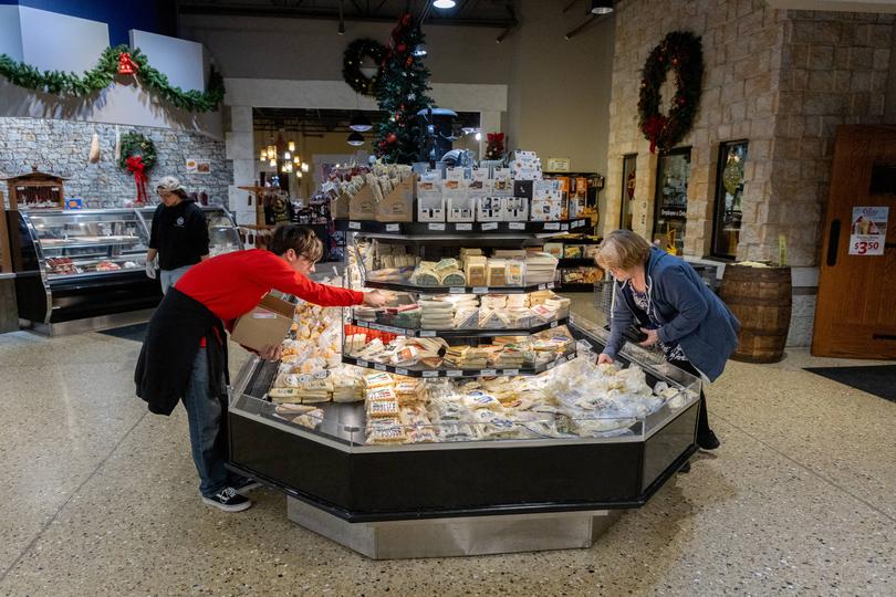 Victor Robin, left, stocks cheese while customers shop at Mars Cheese Castle. 