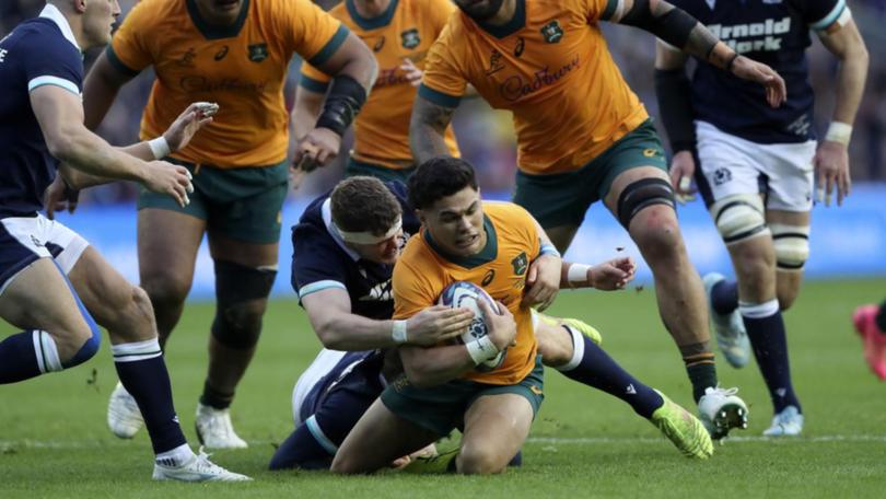 Australia's Noah Lolesio is tackled by Scotland's Scott Cummings.