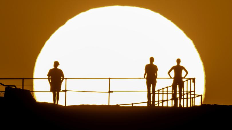 People watch as the sun rises over Ben Buckler Point in Bondi on November 27. A severe heatwave warning has been issued by the Bureau of Meteorology for parts of eastern NSW over the next few days.