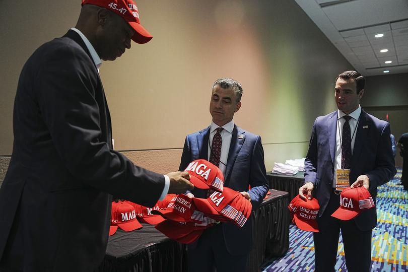 Campaign volunteers stock a table with MAGA hats during a election night event for Donald Trump.