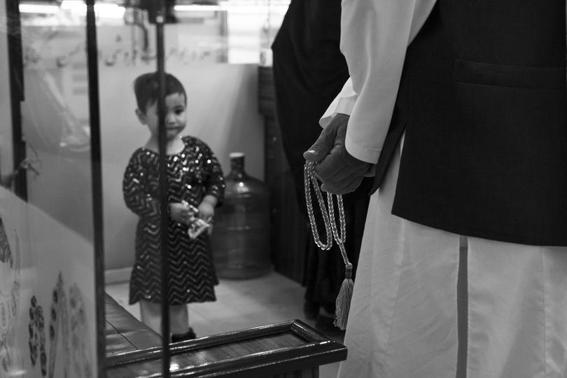 A young girl watches as an officer with the Vice and Virtue Ministry patrols a mall in Kabul. 