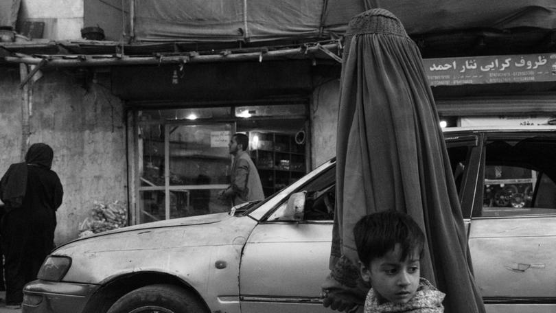 A woman in a burqa walks with her son through Kabul in October. As Afghans living abroad return to visit relatives for the first time since the 2021 Taliban takeover, few seem concerned about women living under increasingly severe restrictions. MUST CREDIT: Carolyn Van Houten/The Washington Post