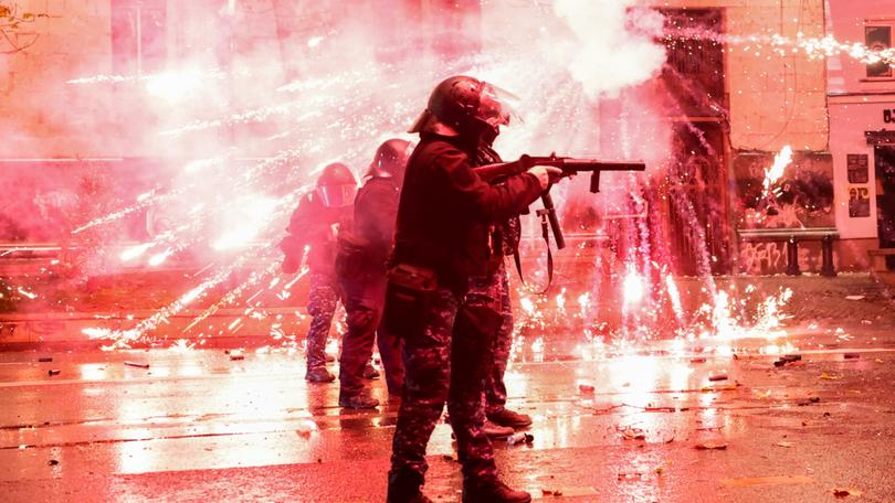 Fireworks shot by protesters explode near police in riot gear firing tear gas during a fourth day of nationwide protests.