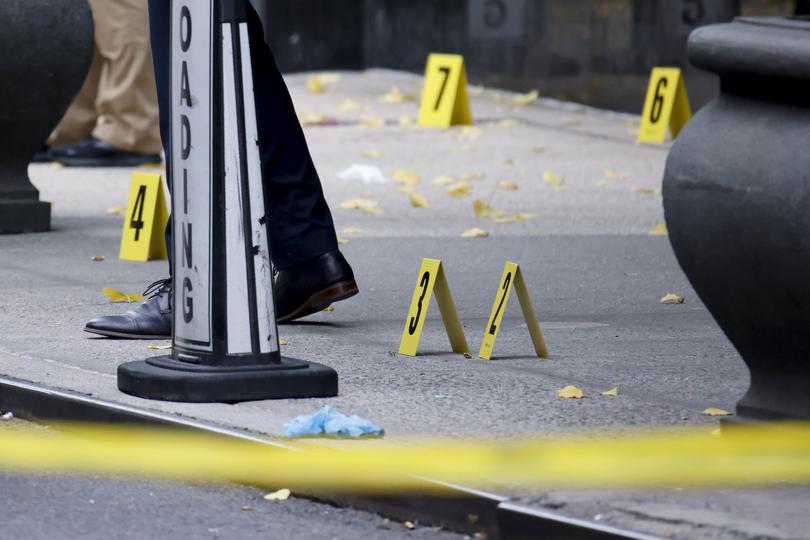 Members of the New York police crime scene unit investigate bullets lying on the sidewalk.