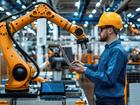 male technician in the factory controls the robotic arm