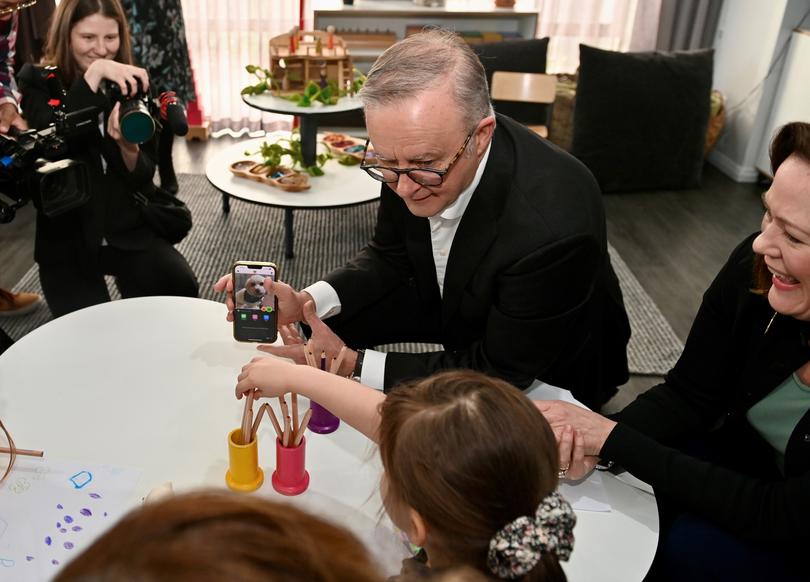 Prime Minister Anthony Albanese shows a photo of his dog, Toto, to children at a Dayton childcare centre during his trip to Perth.