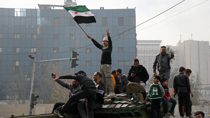 People react to the fall of Syrian regime in Umayyad Square on December 8, 2024 in Damascus, Syria. 