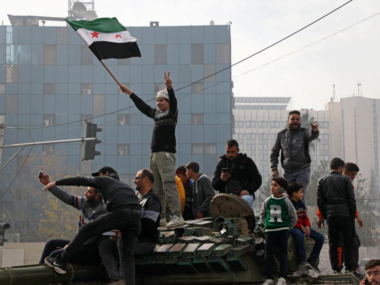 People react to the fall of Syrian regime in Umayyad Square on December 8, 2024 in Damascus, Syria. 