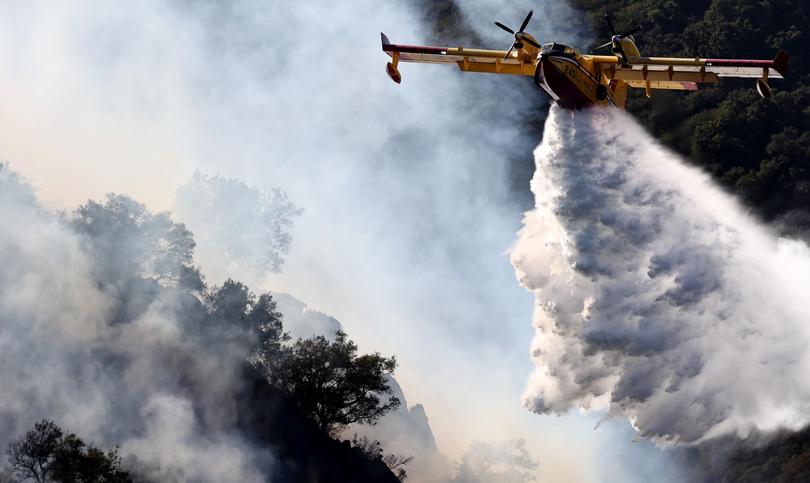 A firefighting aircraft drops water as the Franklin Fire continues to burn near Malibu.