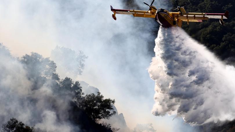 A firefighting aircraft drops water as the Franklin Fire continues to burn near Malibu, California.