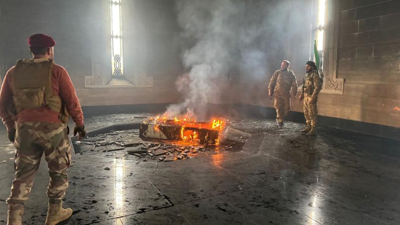 Rebel fighters stand next to the burning coffin of Syria's late president Hafez al-Assad at his mausoleum in the family's ancestral village of Qardaha.