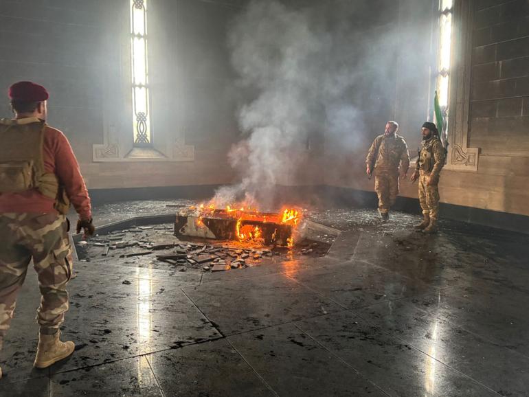 Rebel fighters stand next to the burning coffin of Syria's late president Hafez al-Assad at his mausoleum in the family's ancestral village of Qardaha.